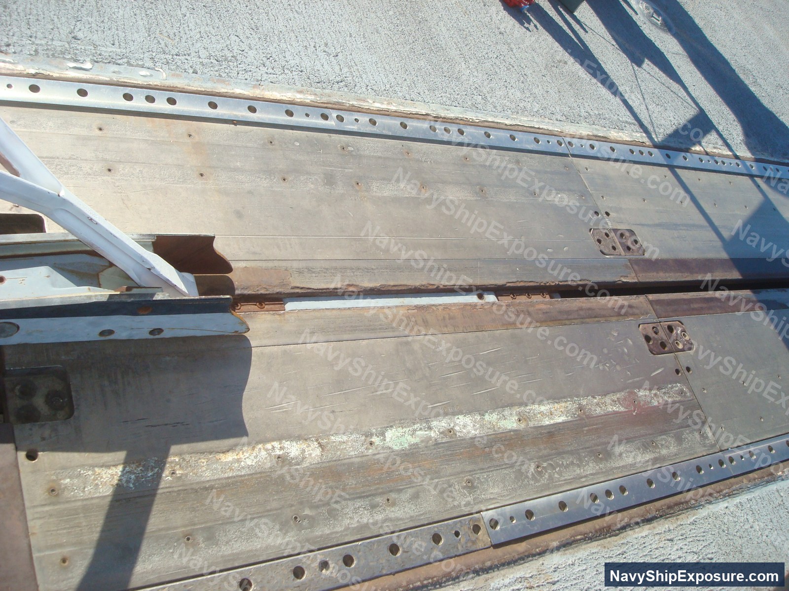Close-up photograph of structural steel beams and angle iron with rivet holes and metal straps, typical of aircraft carrier interior construction and machinery space framework from the WWII-era Essex-class carrier USS Midway.