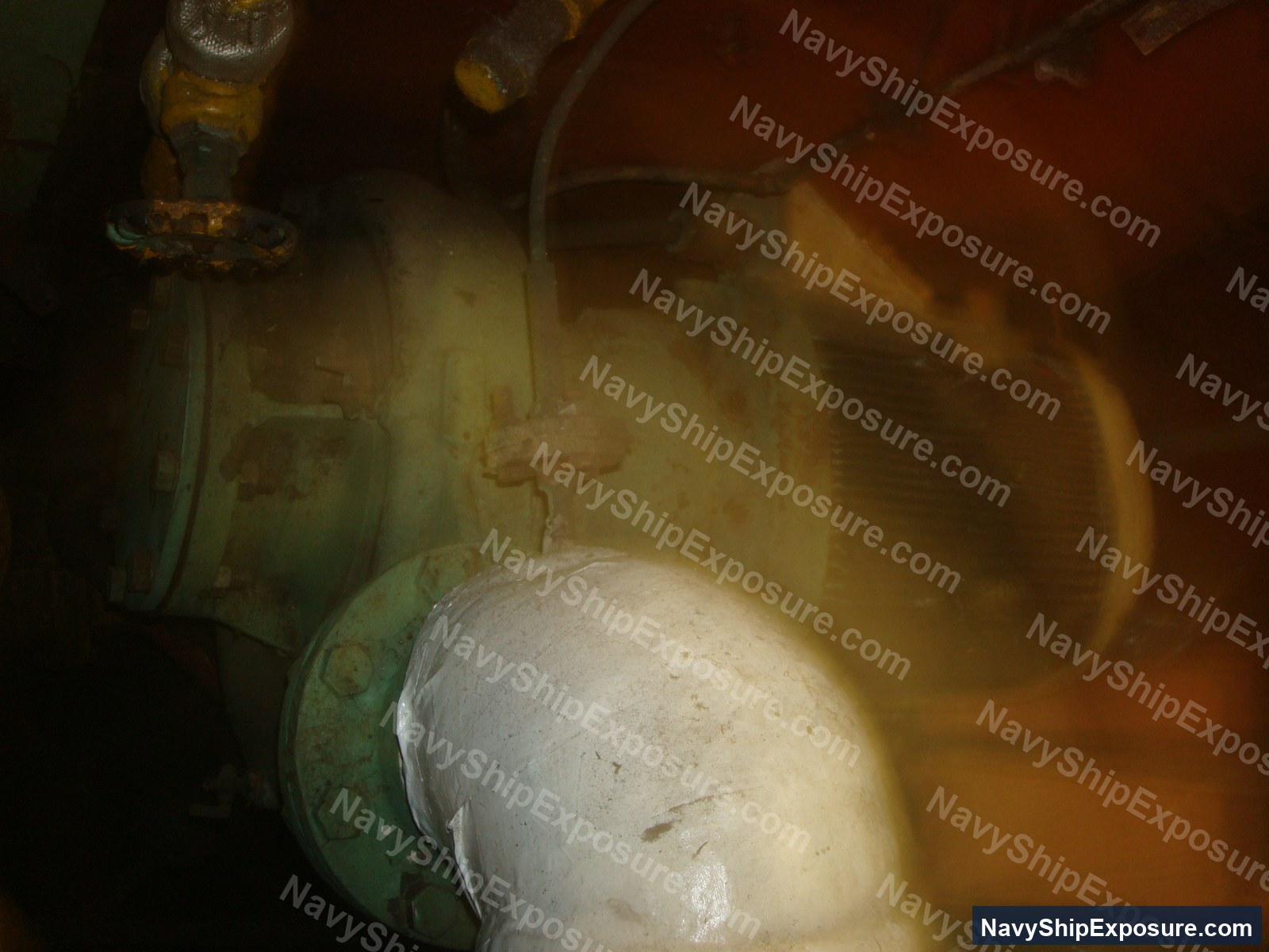 Engine room or machinery space piping with white insulation material (likely asbestos-containing) wrapped around a large cylindrical component, showing typical shipboard equipment configuration from the USS Midway era.