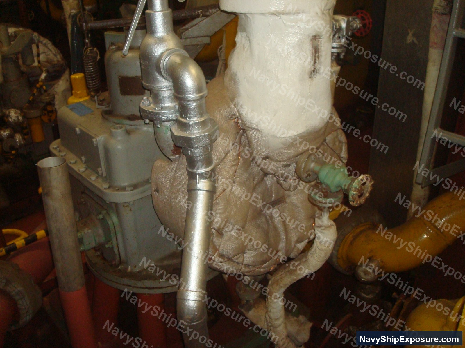 Engine room or machinery space equipment showing insulated piping, valves, and thermal insulation wrapping typical of steam plant systems aboard USS Midway.