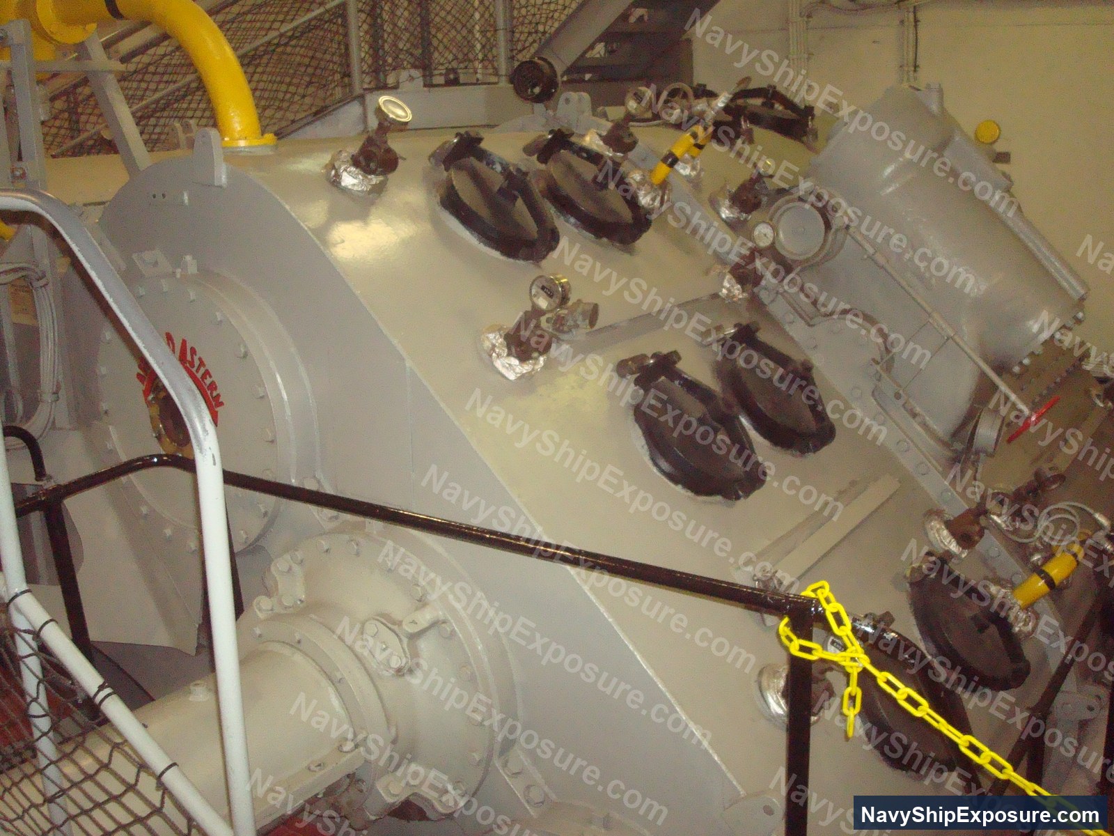 Engine room or machinery space aboard USS Midway showing large industrial pumps or compressors with associated piping, valves, and engineering equipment typical of a 1940s-era aircraft carrier's propulsion or support systems.