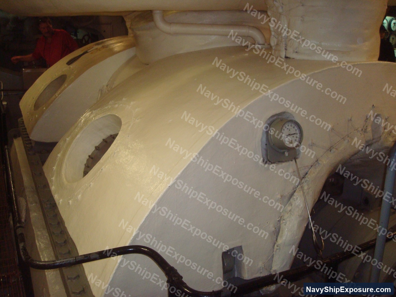 Interior view of a large cylindrical vessel or tank with pressure gauge and piping, likely boiler or steam-related machinery from USS Midway's engineering spaces.