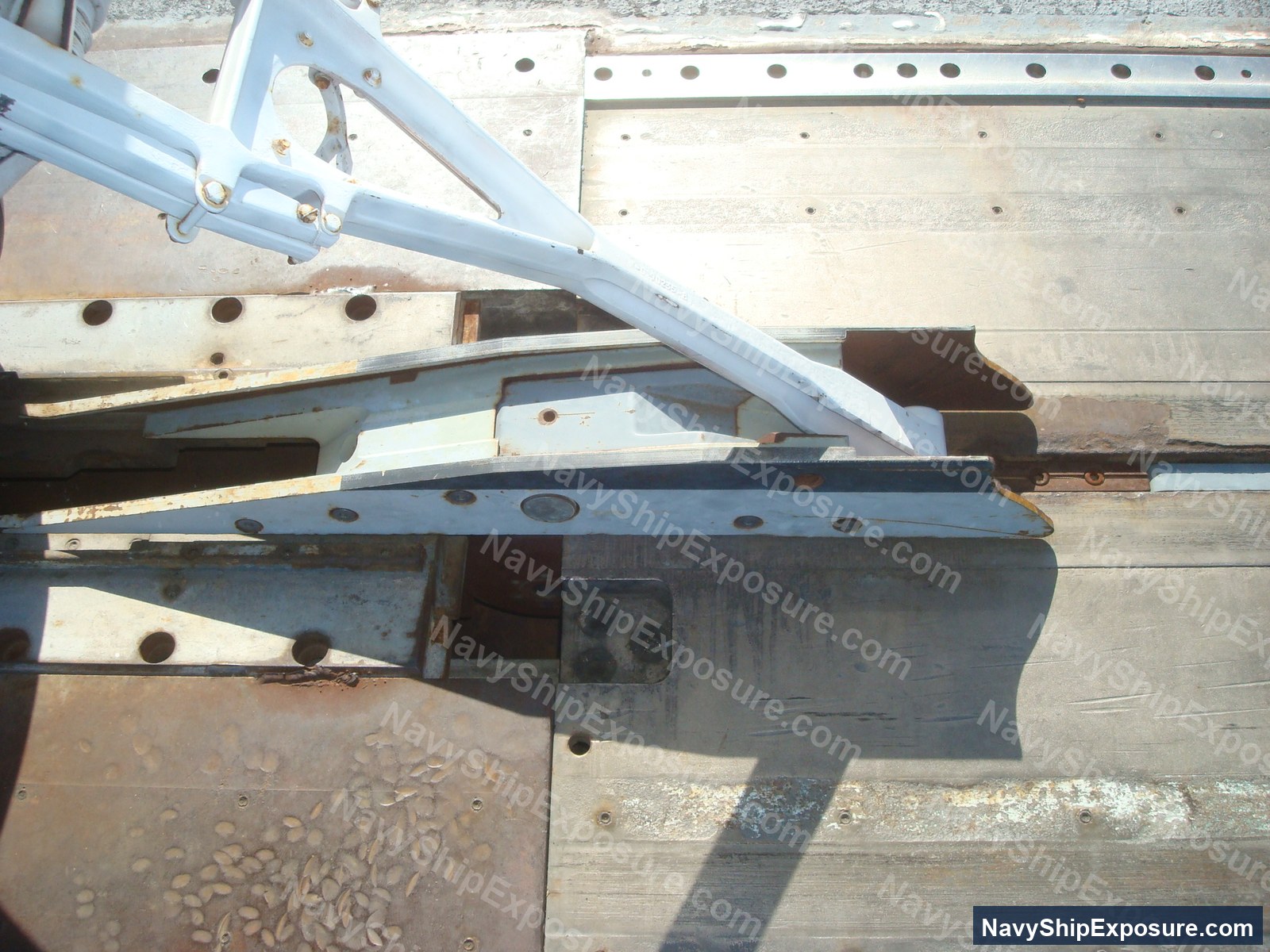 Close-up photograph of ship machinery components including metal structural elements, piping, and mechanical fixtures from USS Midway's engine or machinery spaces.