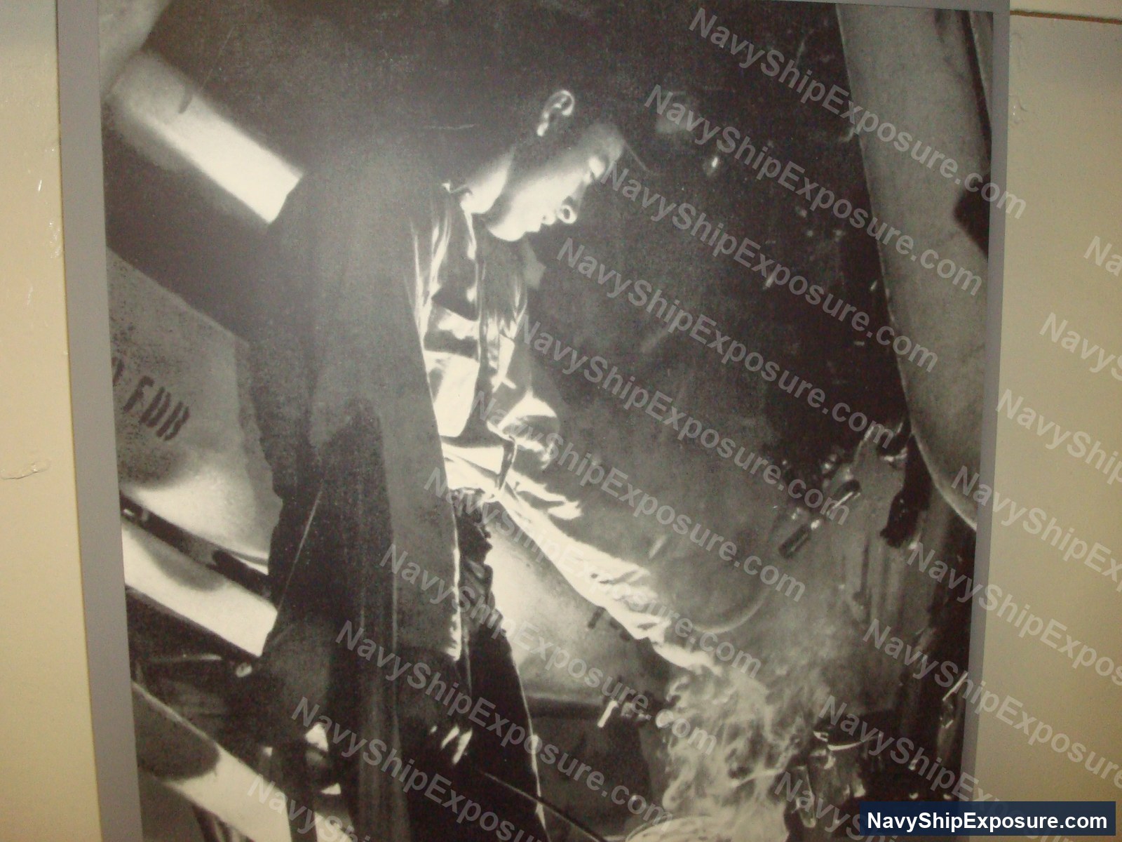 Black and white photograph of a USS Midway boiler room showing personnel working near large cylindrical boiler equipment and steam piping systems.