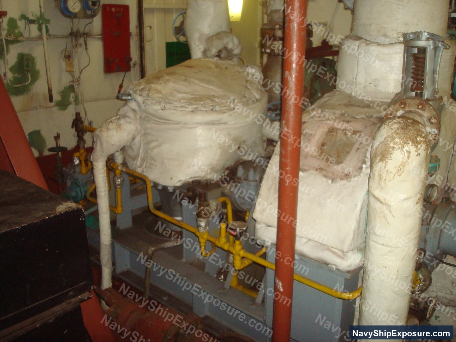 Boiler room machinery space aboard USS Midway showing large cylindrical boilers with insulation wrapping and yellow safety railings.