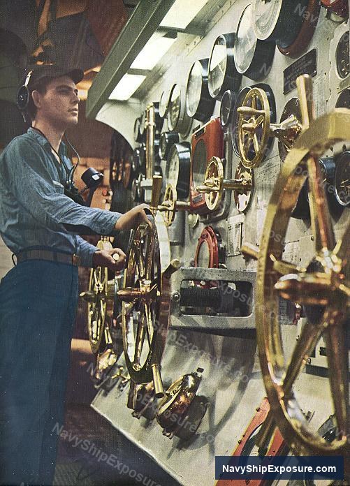 A worker operates machinery in an engine room or machinery space aboard USS Midway, with multiple brass fittings and mechanical components visible along the wall.