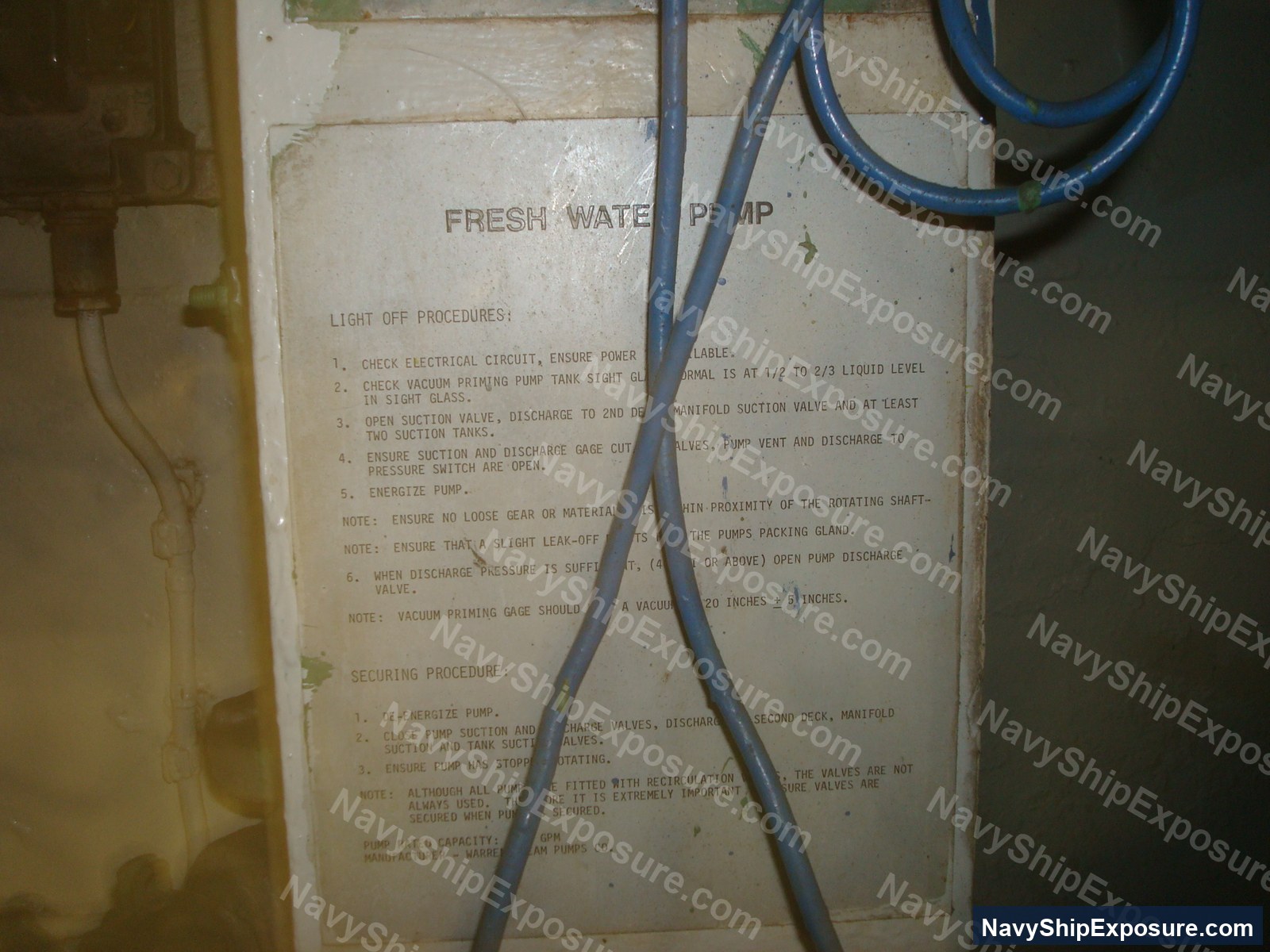 Instruction placard for fresh water pump operations aboard USS Midway, detailing light-off procedures, securing procedures, and pump specifications with blue hoses crossing the laminated label.