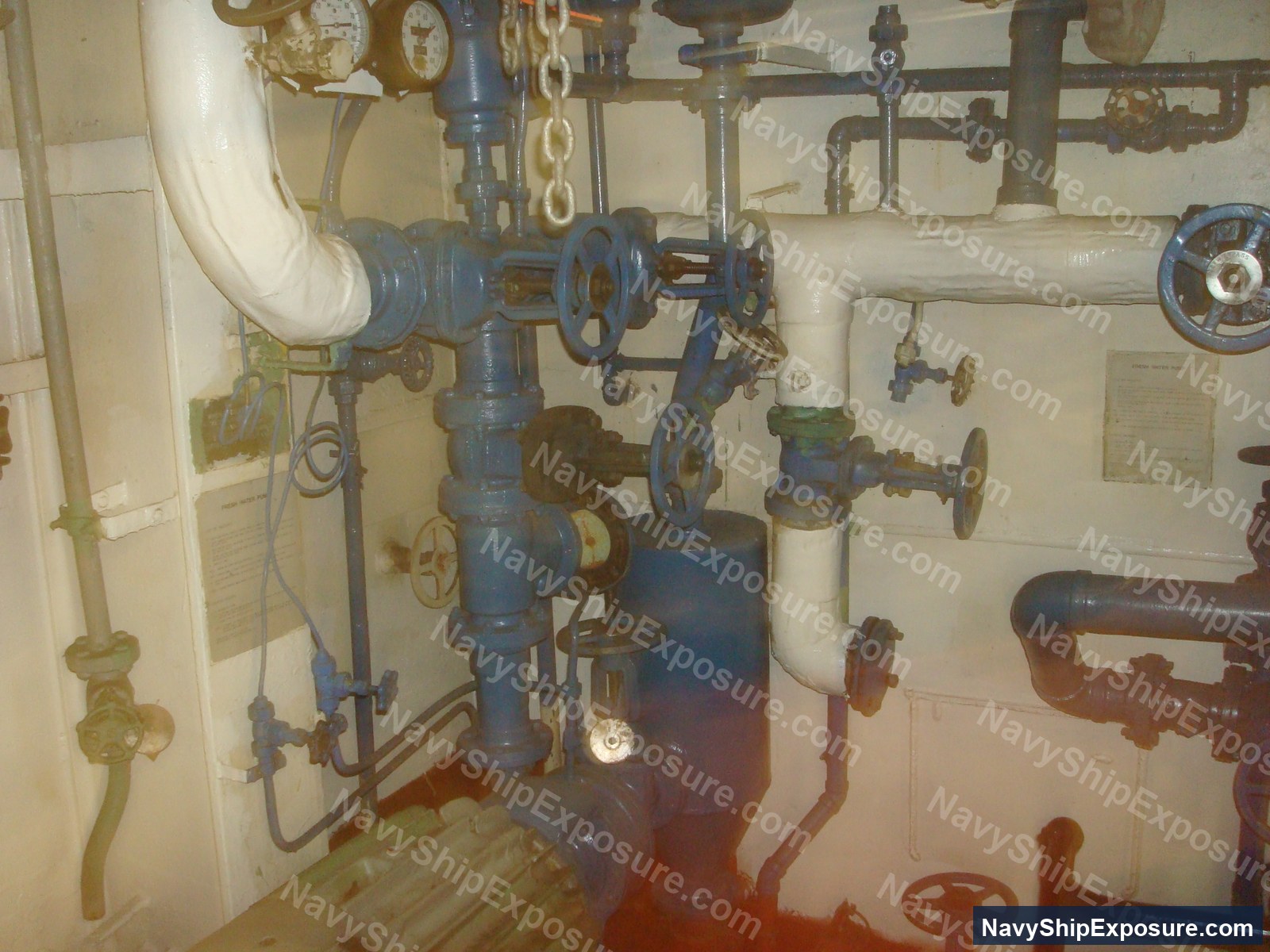 Interior view of USS Midway engine room or machinery space showing complex piping systems, valves with hand wheels, and steam distribution equipment typical of a World War II-era aircraft carrier's propulsion system.