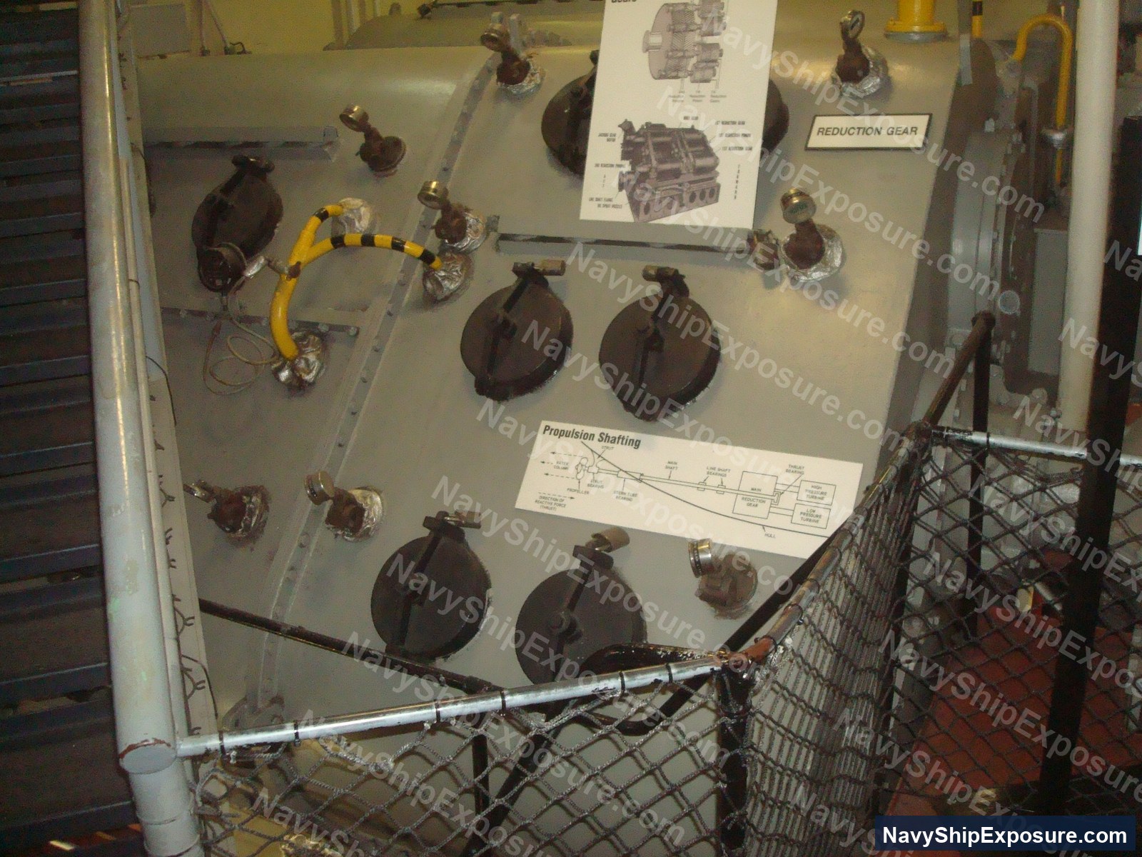 Museum display panel showing propulsion system components including reduction gear, propulsion shafting, and various mechanical assemblies from USS Midway's engineering spaces.