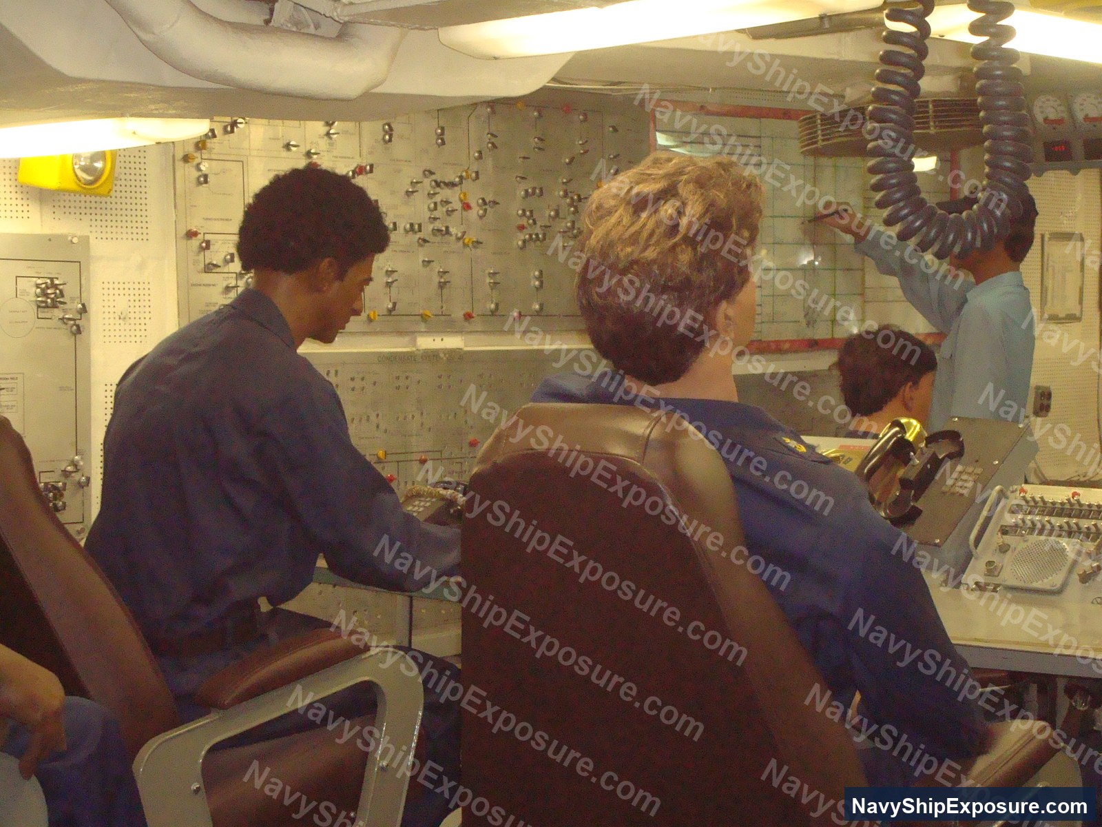 Engine room or machinery control space aboard USS Midway showing electrical control panels, instrumentation boards, and crew members operating engineering systems typical of 1940s-1960s naval vessels.