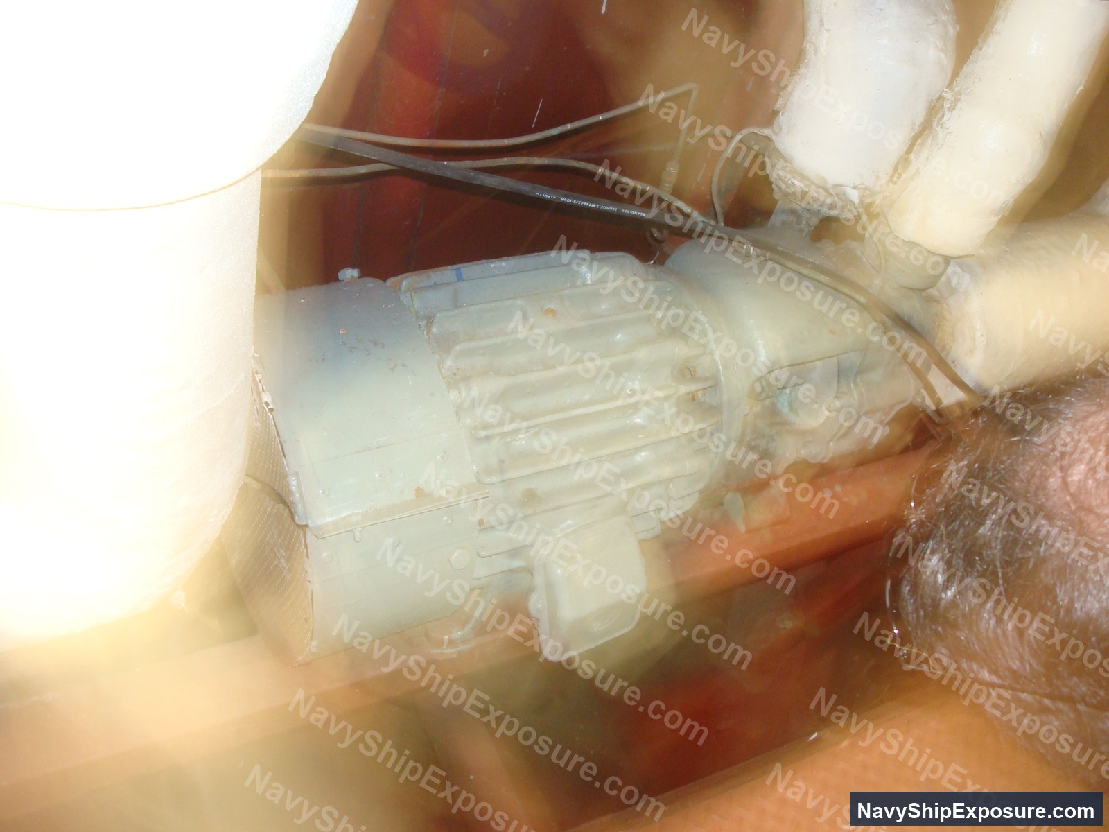 Close-up photograph of what appears to be an electric motor or pump component with visible wiring, likely from the USS Midway's machinery spaces.