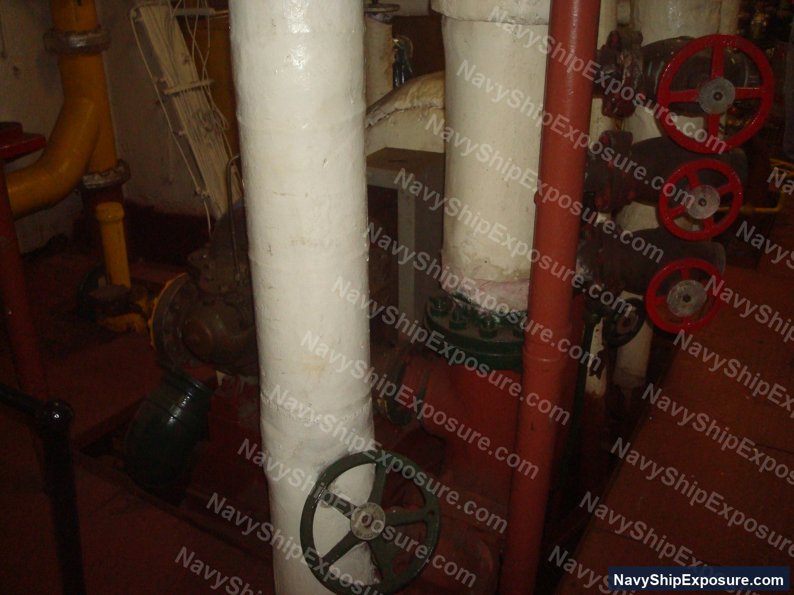 Engine room or machinery space aboard USS Midway showing large cylindrical pipes with manual valve wheels, typical of steam propulsion system components from the 1945-1992 era vessel.