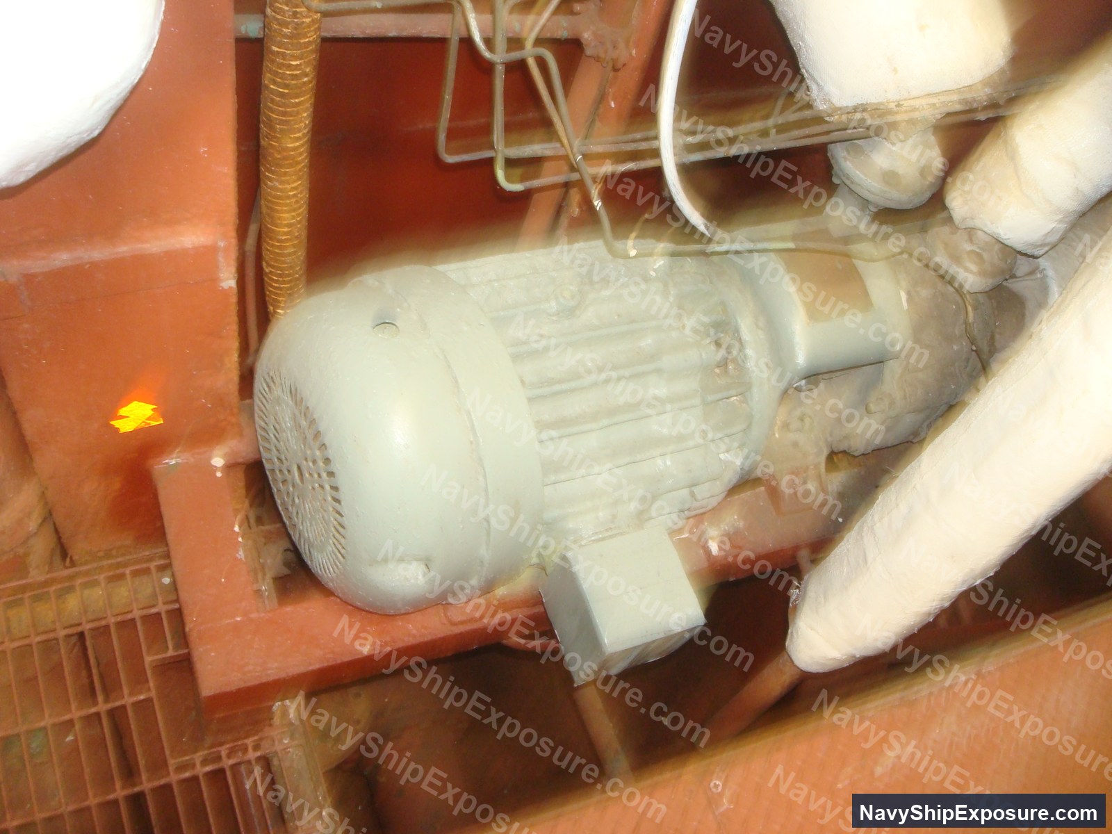 Electric motor mounted on red structural framing in an engine room or machinery space of USS Midway, showing typical 1940s-era naval equipment installation with visible piping and wiring.