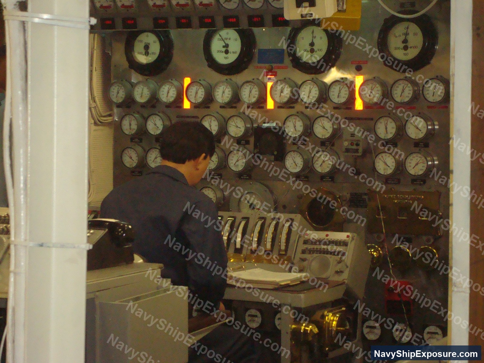 Engine room or machinery control space aboard USS Midway showing numerous analog gauges and monitoring instruments typical of 1945-1992 era naval vessel propulsion systems.